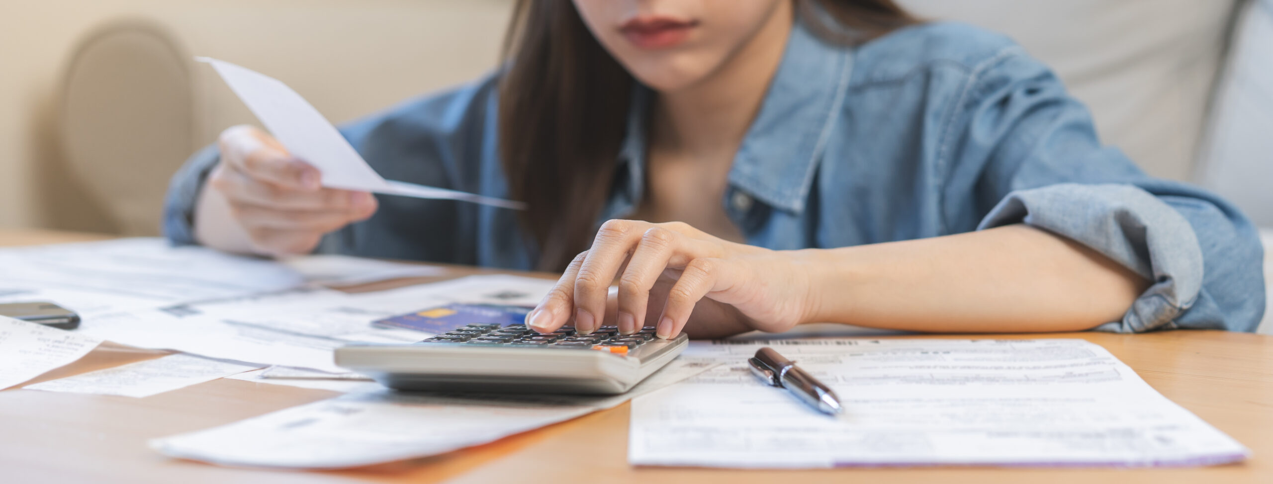 women sitting at desk with calculator looking at business finances